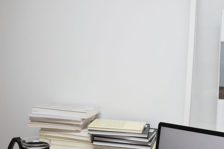 A laptop, books and coffee on a tidy desk