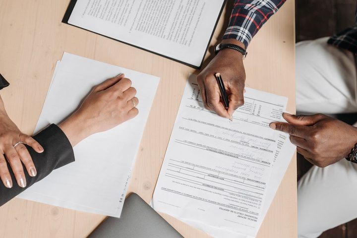 People reviewing and signing immigration paperwork at a desk