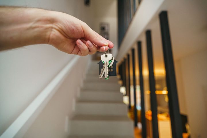 A hand holding house keys inside a home