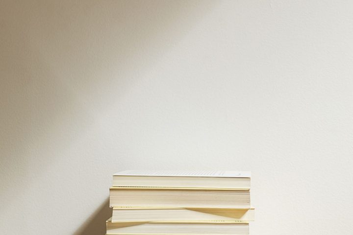 A stack of books on a wooden desk